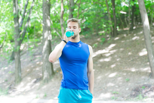 Refreshing vitamin cocktail. Man athletic body hold bottle water. Man athlete sport clothes care about water balance. Healthy lifestyle. Athlete drink water after training outdoors. Making sip - Фото, зображення