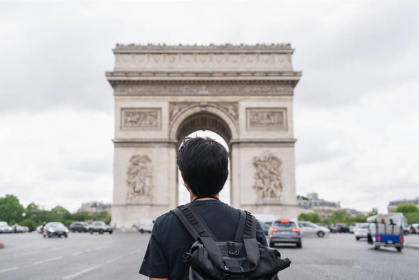 um homem com mochila olhando para o Arco do Triunfo, famoso marco e destino de viagem em Paris, França. Viajar na Europa no verão
 - Foto, Imagem