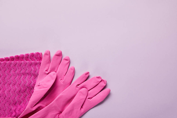 top view of pink rag, rubber gloves on purple background  - Φωτογραφία, εικόνα