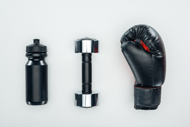 top view of black sport bottle near dumbbell and boxing glove isolated on white  - Foto, afbeelding