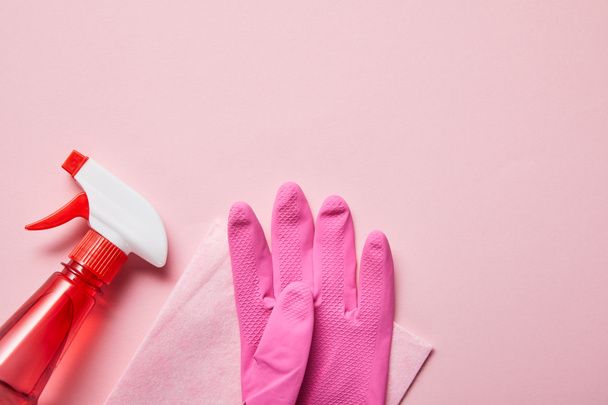 top view of pink rag, rubber glove and bottle with spray on pink background  - Foto, afbeelding