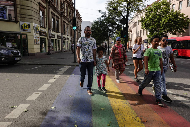 ビリニュス、リトアニア 旧市街の家族は、プライドの色でマークされた通りを横断します. - 写真・画像