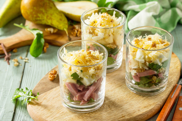 Salade met peer, ham, ei, walnoten, vruchten en rucola op rustiek - Foto, afbeelding
