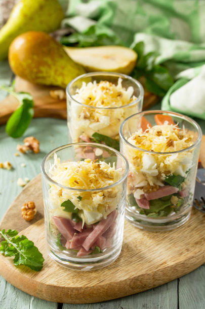 Salat mit Birne, Schinken, Ei, Walnüssen, Früchten und Rucola auf rustikalem - Foto, Bild