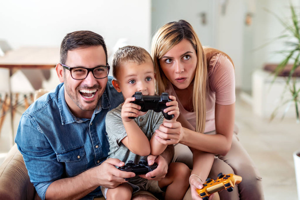 Szczęśliwa rodzina gra w gry wideo w domu i zabawy razem. - Zdjęcie, obraz
