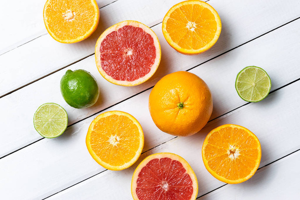 Halved citrus fruit on a white wood table background  - Foto, Imagen