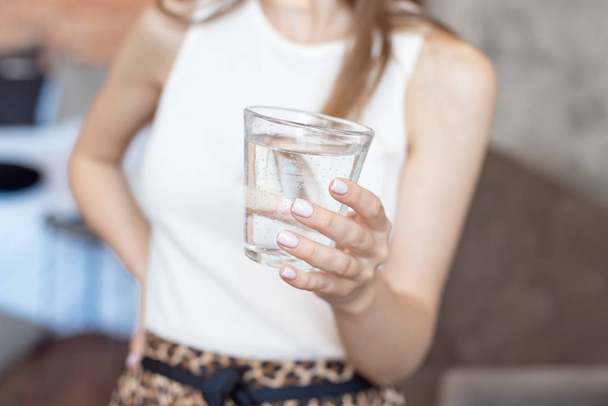 close-up woman with slim body holding a glass of water, rear veaw. - Zdjęcie, obraz