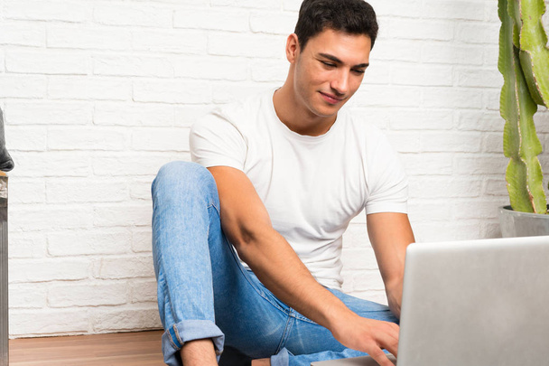 Handsome man sitting on the floor with his laptop - Foto, Imagen