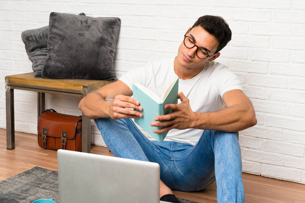 Красивый мужчина сидит на полу со своим ноутбуком
 - Фото, изображение