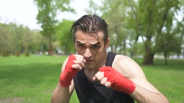 4. Muscular man boxer training with  shadow. Blows in camera. City park outdoor steady shot - Footage, Video