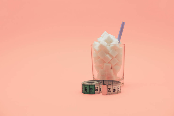 Склянка, наповнена кубиками цукру з соломою на красивому персиковому фоні - концепція здорового харчування
. - Фото, зображення