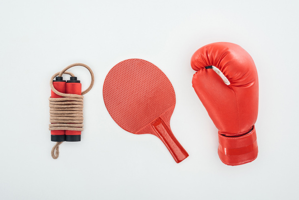 top view of jumping rope near ping pong racket and red boxing glove isolated on white  - Foto, Imagem