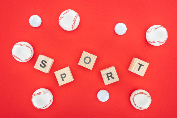 litery sportowe na drewnianych kostkach w pobliżu softballs izolowane na czerwono  - Zdjęcie, obraz