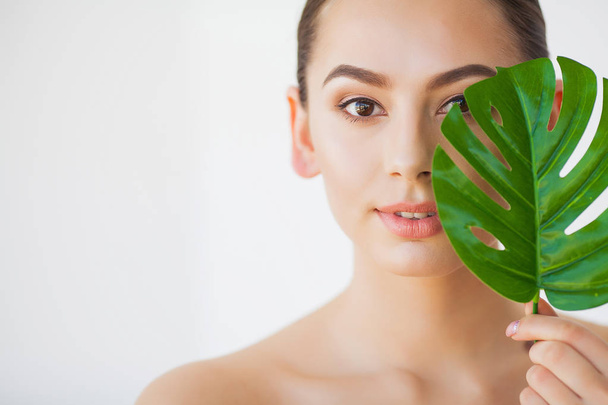 Spa care. Young pretty brunette woman with big green leaf - Fotoğraf, Görsel