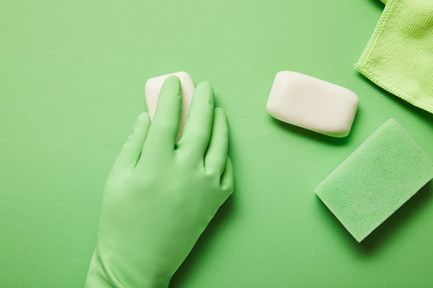 bijgesneden aanzicht van de mens in rubberen handschoen met witte zeep  - Foto, afbeelding