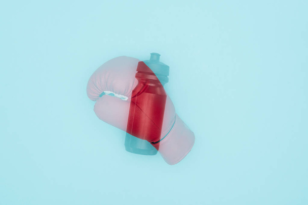kırmızı boks eldiveni ve spor şişesi nin mavi üzerine izole çifte pozlama  - Fotoğraf, Görsel