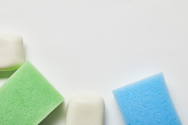 top view of white soaps, green and blue sponges  - Fotó, kép
