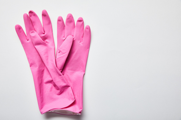 top view of pink rubber gloves on grey background with copy space  - 写真・画像