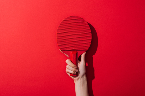 cropped view of woman holding ping pong racket on red  - Foto, Imagen