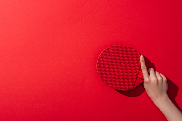 cropped view of woman holding wooden table tennis racket on red  - Photo, Image