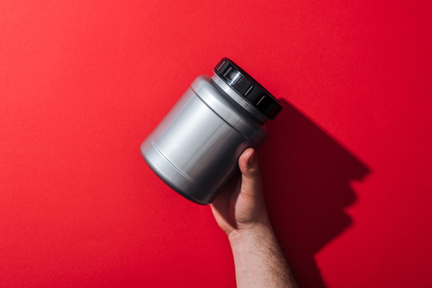 cropped view of man holding grey jar on red  - 写真・画像