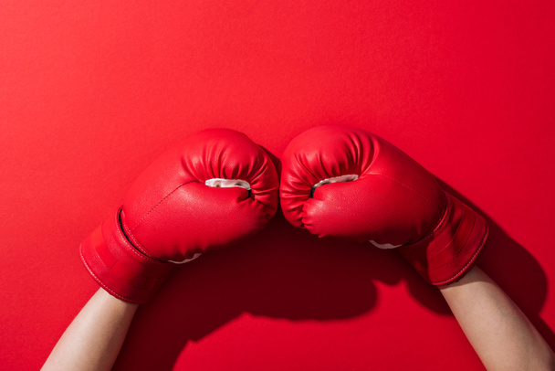 cropped view of woman in pair of boxing gloves on red  - Foto, imagen