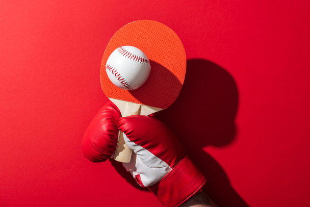 vue recadrée de la femme en gant de boxe tenant raquette de tennis et baseball sur rouge
  - Photo, image