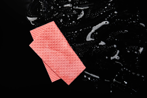 top view of pink rag with foam on black background  - Zdjęcie, obraz
