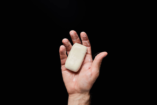 top view of man holding white soap isolated on black - Foto, immagini