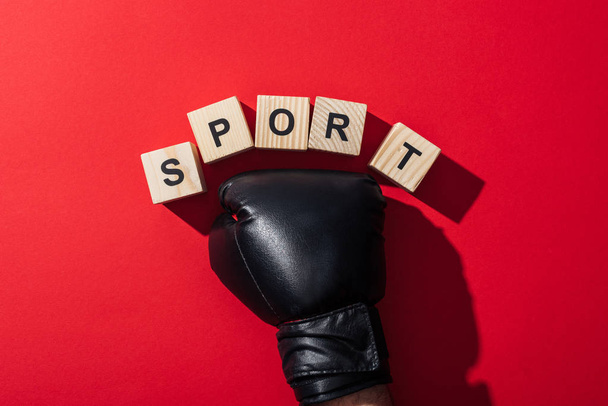 cropped view of man in boxing glove near wooden cubes with sport lettering on red  - Foto, Imagem