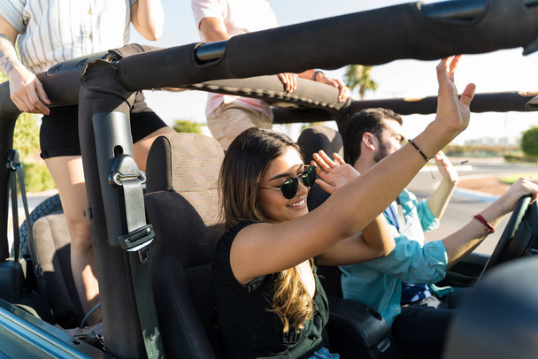Latinalainen nainen nauttii musiikista ajomatkan aikana ystävien kanssa kesällä
 - Valokuva, kuva