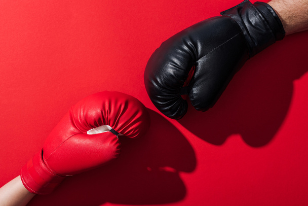cropped view of man and woman in leather boxing gloves on red  - Фото, зображення
