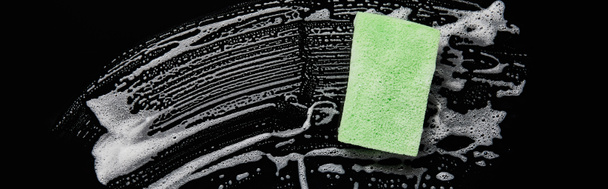 panoramic shot of green and colorful sponge with foam on black background  - Photo, Image