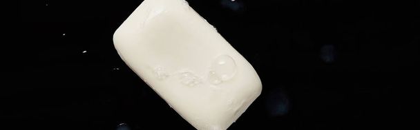 panoramic shot of white soap with droplets on black background  - Фото, зображення