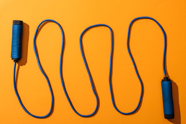 top view of blue and waved skipping rope on yellow  - Foto, afbeelding