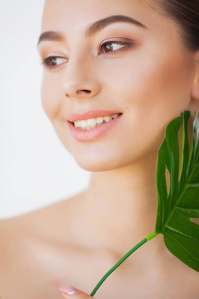 Spa care. Young pretty brunette woman with big green leaf - Foto, imagen