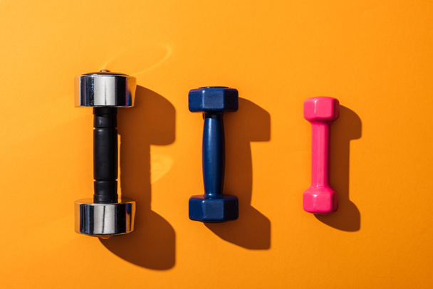 top view of black, blue and pink metallic dumbbells on yellow  - Photo, Image