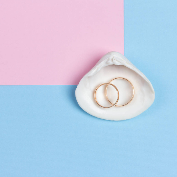 wedding rings in seashell on pastel blue pink background, minimalistic design, top view flat lay - Foto, afbeelding