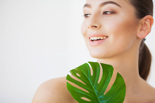 Spa care. Young pretty brunette woman with big green leaf - Foto, imagen