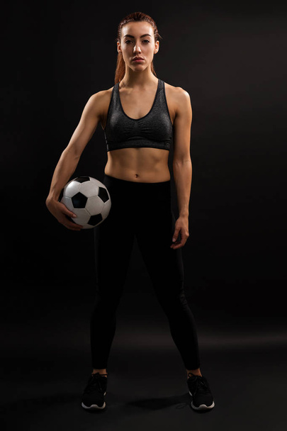 Full length of Caucasian female soccer player holding ball against plain background - Valokuva, kuva