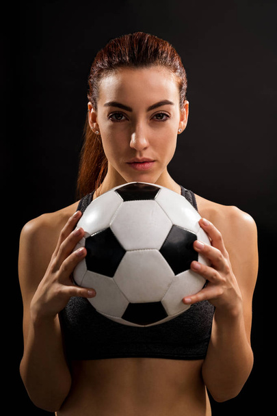 Πορτρέτο του σίγουρος νέος θηλυκός ποδοσφαιριστής κρατώντας μπάλα στο στούντιο - Φωτογραφία, εικόνα