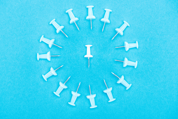 top view of blue paper clips with white paper clip in middle isolated on blue, violence concept - Fotografie, Obrázek