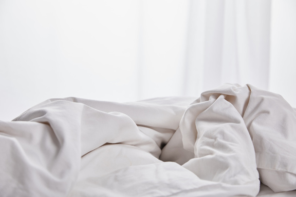 cobertor branco amassado na cama perto de cortina
 - Foto, Imagem
