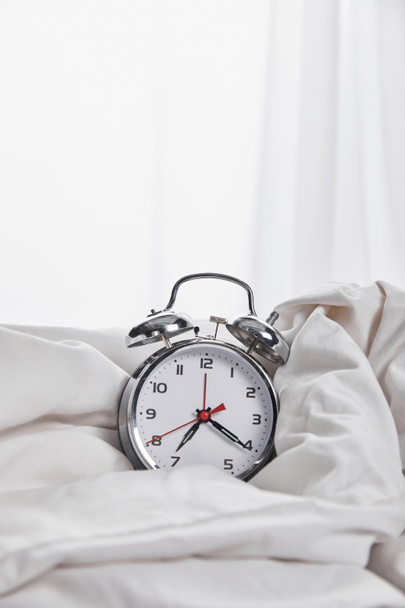 silver alarm clock in blanket in white bed  - Photo, Image