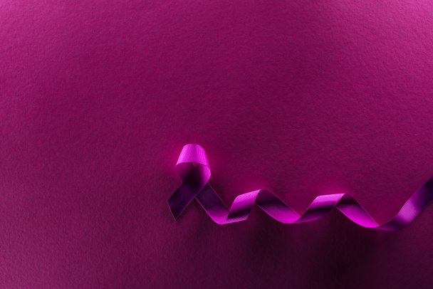 bovenaanzicht van paars lint op paarse achtergrond in schaduw - Foto, afbeelding
