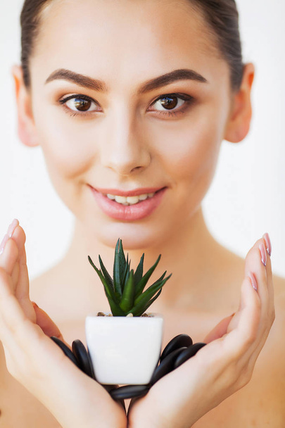 Уход за кожей. Лицо красавицы с здоровой кожей и зеленым растением
 - Фото, изображение