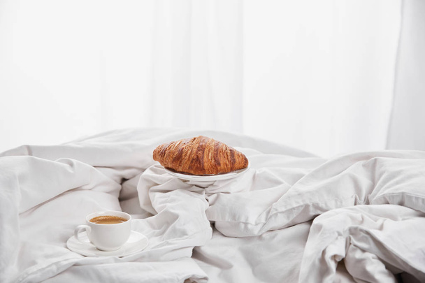 свежий круассан с кофе в белой кровати на утро
 - Фото, изображение