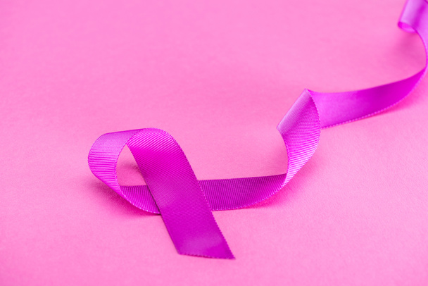 purple ribbon on pink background, violence concept - Foto, afbeelding
