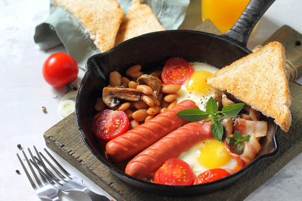 Desayuno en inglés con huevos revueltos con tocino, frijoles, champiñones
 - Foto, imagen