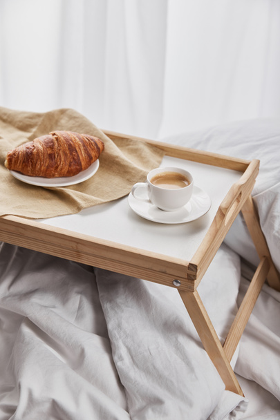 fresh croissant with coffee on wooden tray in bed at morning - Zdjęcie, obraz
